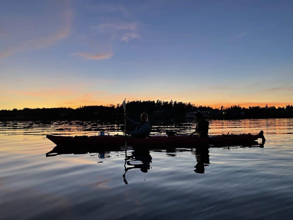 Two people in a kayak as the sun sets.