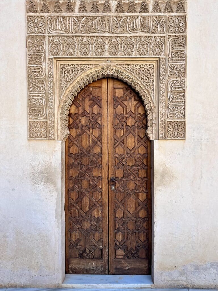 A decorative wooden door carved with a Morroccan eight-pointed star pattern.