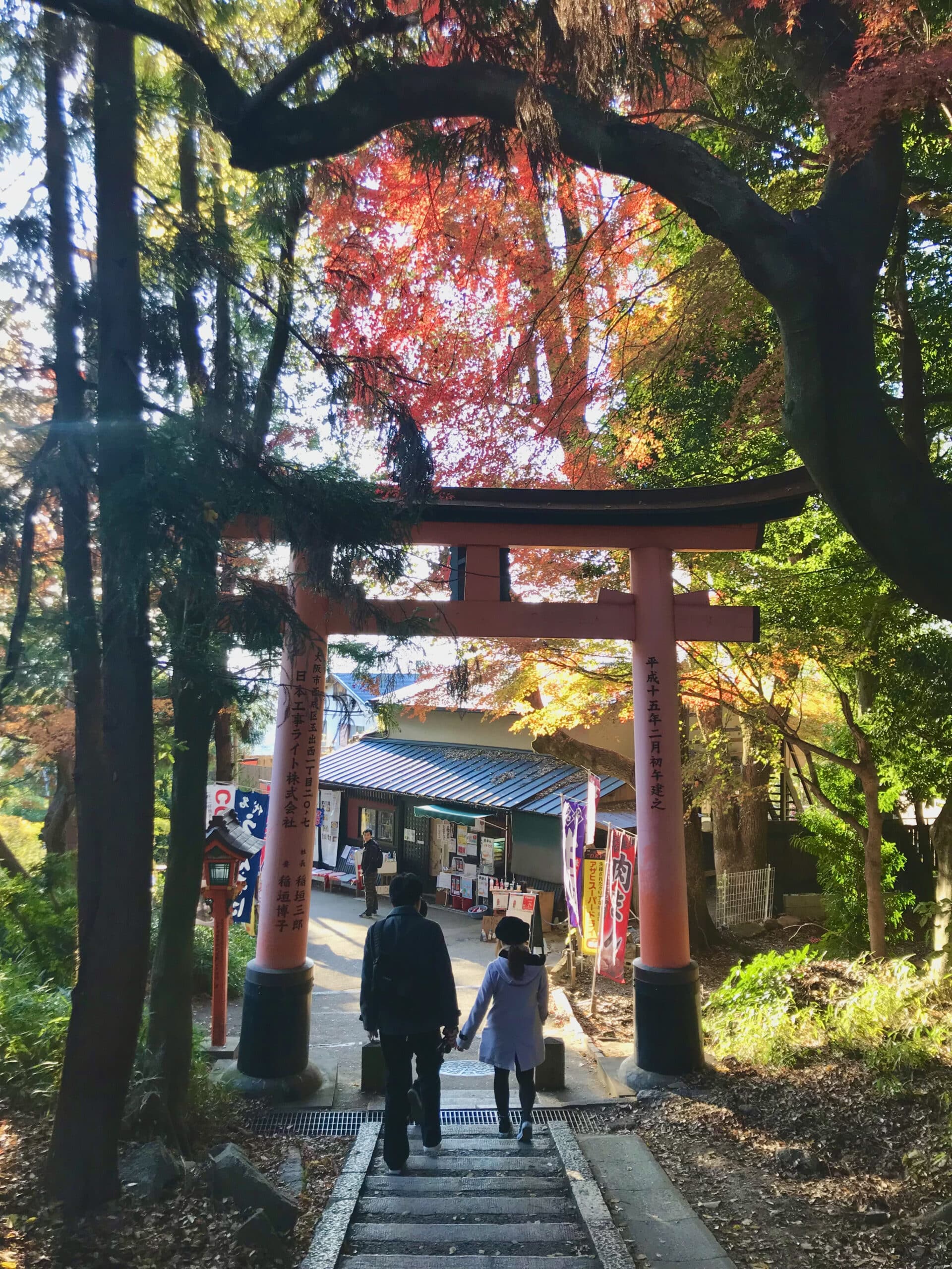 A couple walking beneath a torii gate at Fushimi Inari Taisha