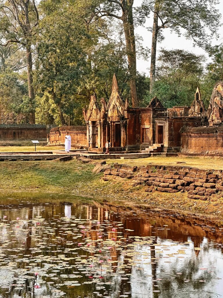 A monk stands at the entrance of Banteay Srei Temple at sunrise in the northern part of Angkor Wat Archaeological Park.
