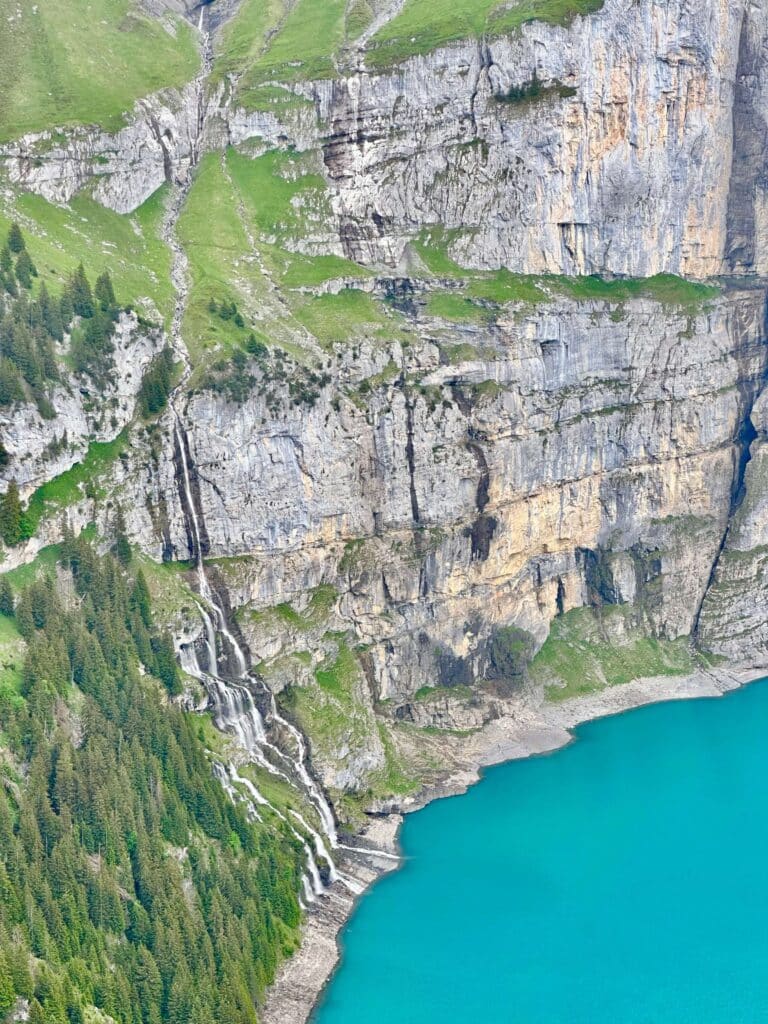 A waterfall cascades into the Oeschinen Lake