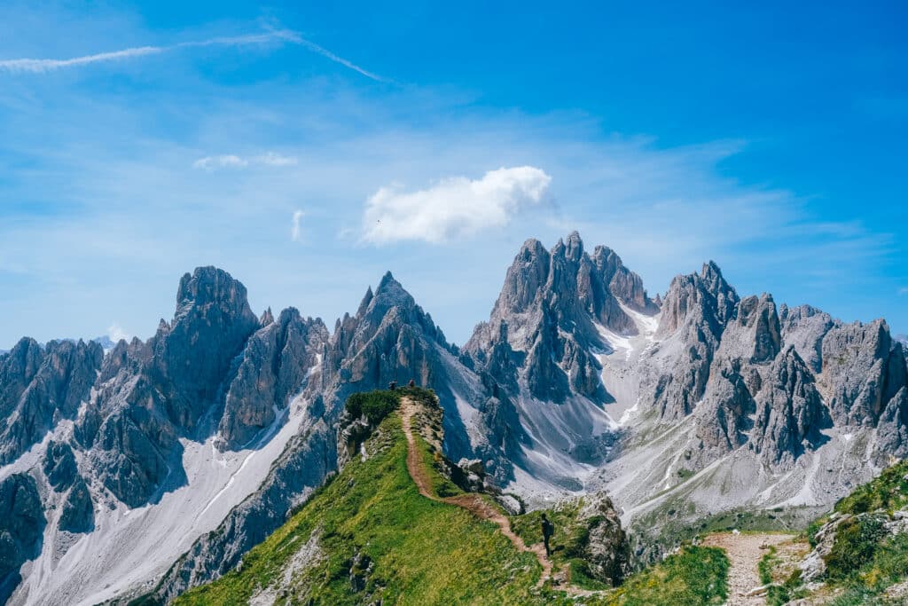 Curving grassy ridge leading toward the dramatic Cadini di Misurina spires in the Italian Dolomites on a summer afternoon
