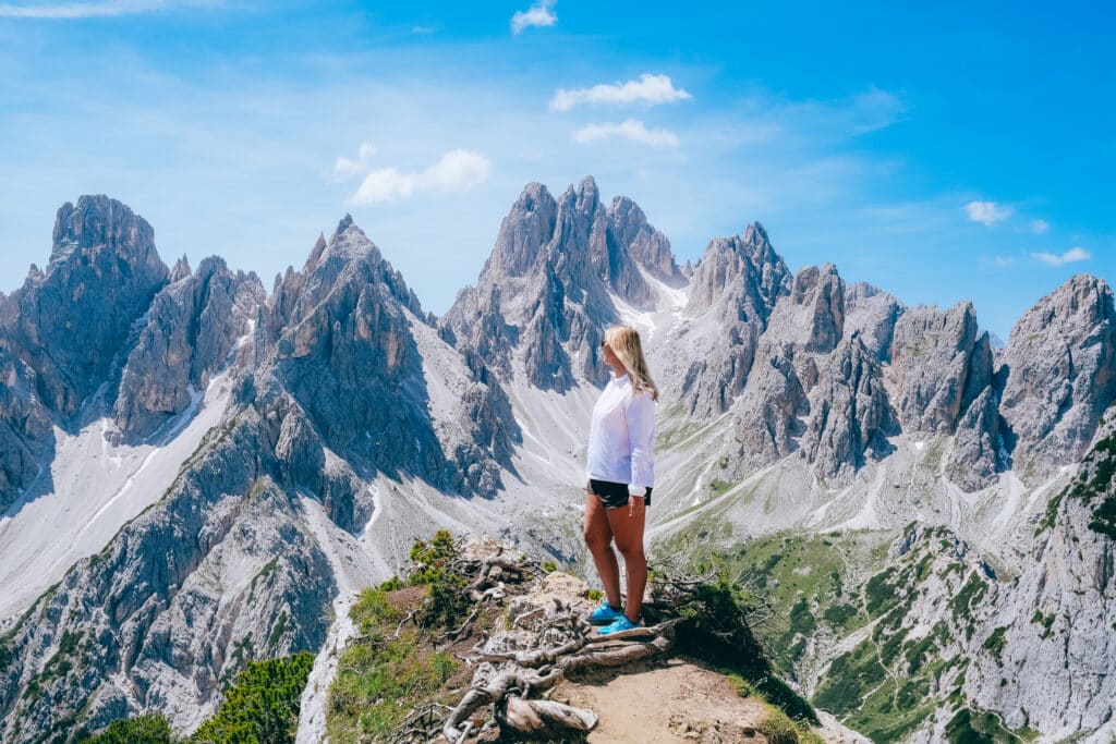 Woman in profile standing on a rocky outcrop and looking across the Cadini di Misurina peaks in the Italian Dolomites