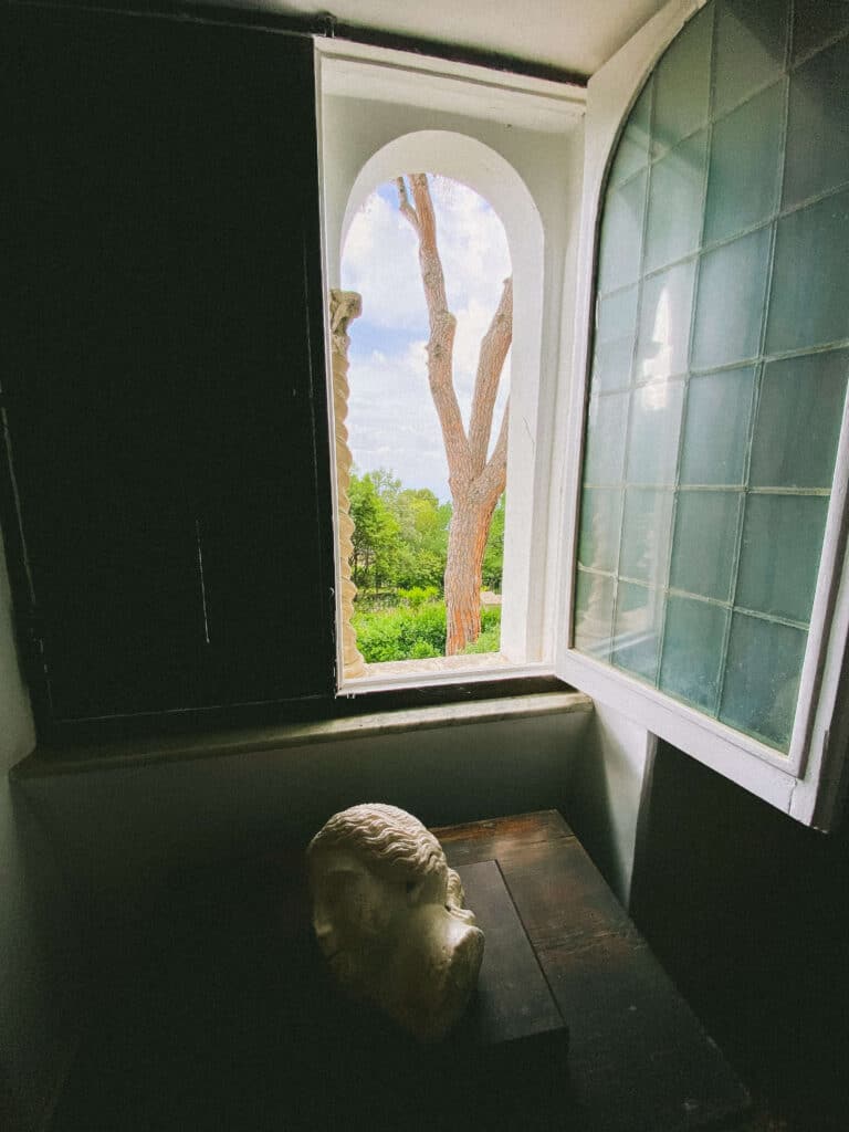 A marble bust illuminated in the sun rays that are streaming through an open window