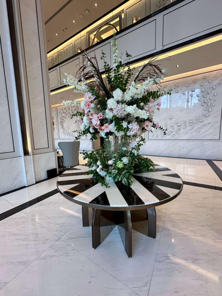 Modern floral centerpiece in the Eastin Grand Hotel Phayathai lobby, placed on a striped round table with elegant marble backdrop