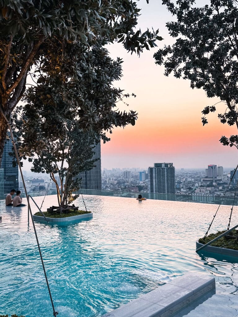 Rooftop infinity pool lined with olive trees and skyline views at Eastin Grand Hotel Phayathai during golden hour
