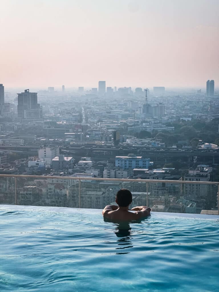 Guest enjoying a quiet swim at the infinity pool at Eastin Grand Hotel Phayathai with city views at dusk