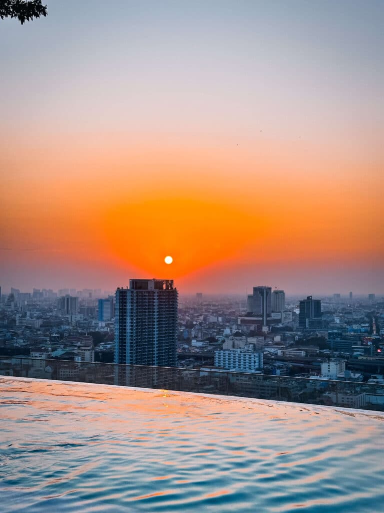 Vibrant sunset view over the Bangkok skyline from the rooftop infinity pool at Eastin Grand Hotel Phayathai