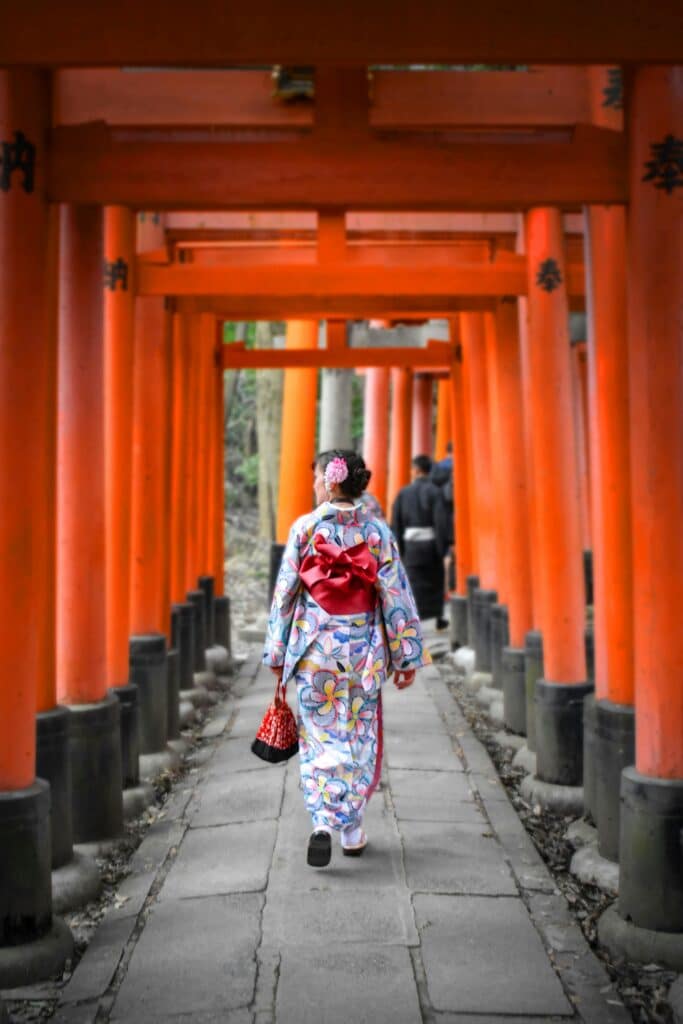 Woman in kimono underneath torii at Fushimi Inari