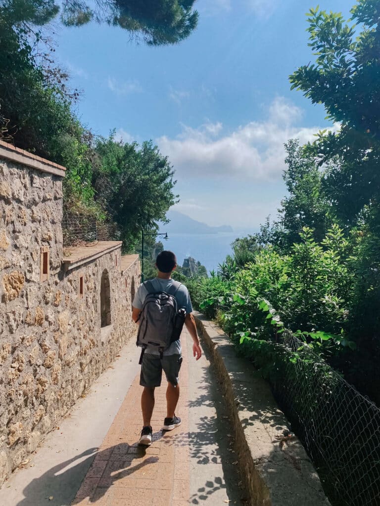 Walking along a stone path near Capri town toward Arco Naturale, shaded by trees
