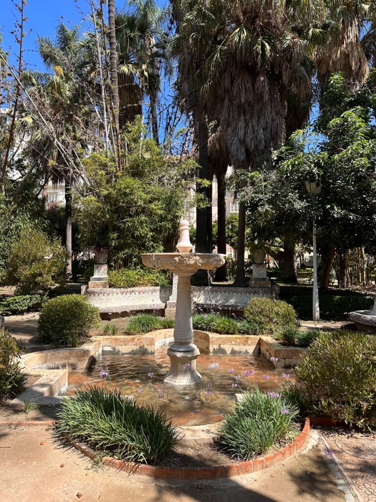 A fountain surrounded by tropical foliage in a public park in Malaga
