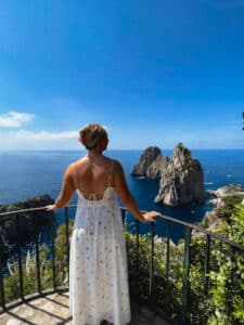 A hiker taking in the view of the La Fontelina Beach Club from an overlook along the Via del Pizzolungo / Via Tragara