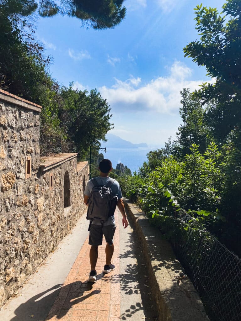 Walking along a stone path near Capri town toward Arco Naturale, shaded by trees