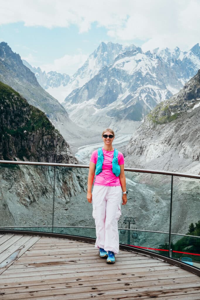 Traveler in pink jacket standing on the Montenvers platform, looking out over the Mer de Glace glacier.