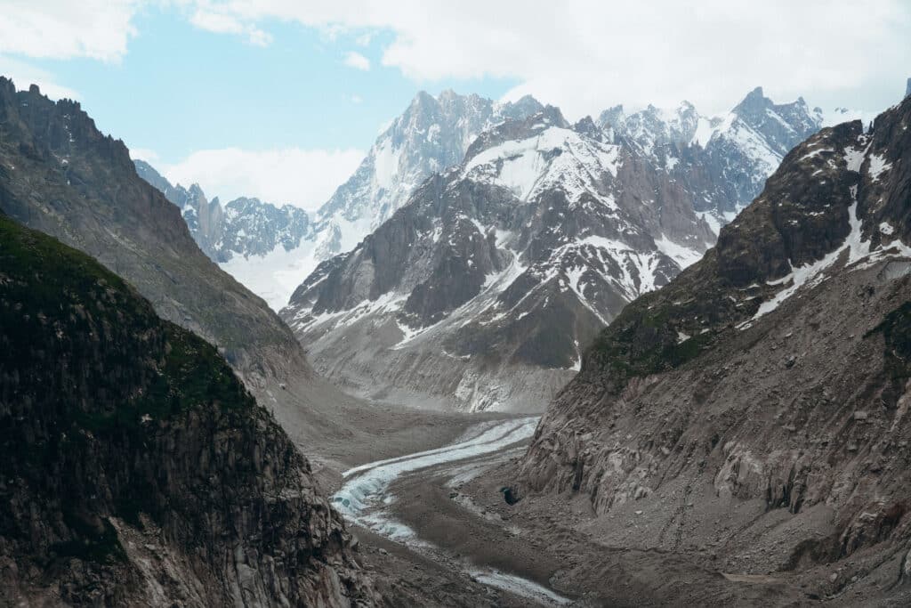Panoramic view of the Mer de Glace cutting through steep valley walls in the French Alps.
