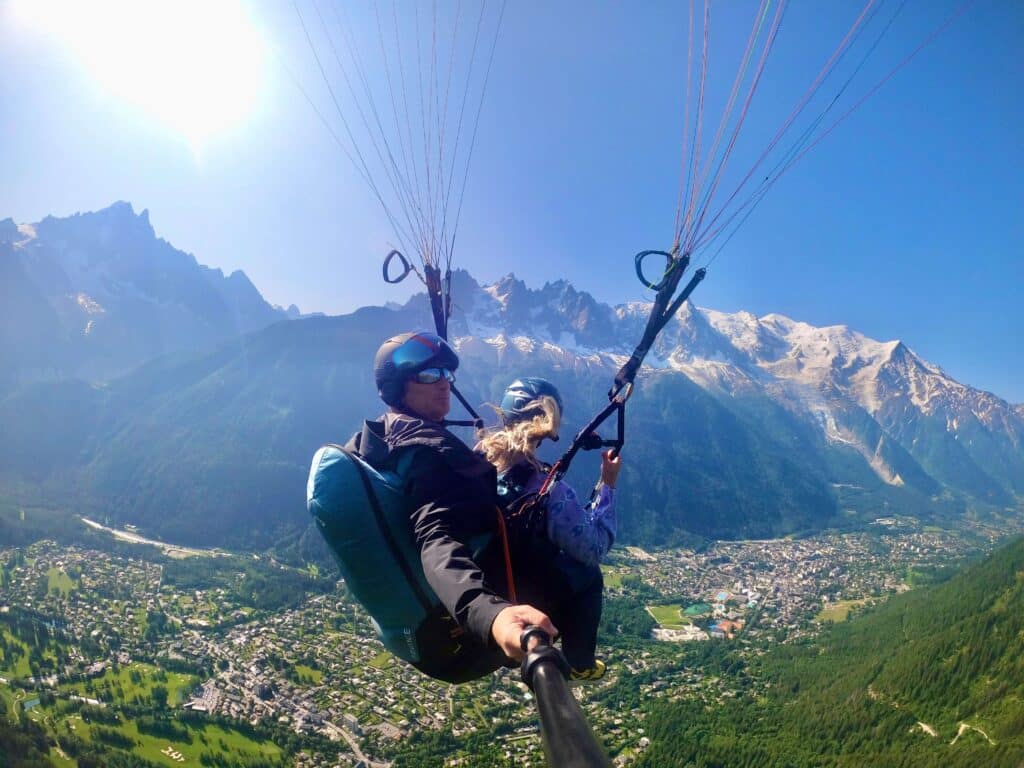 Paraglider mid-flight with Chamonix valley and alpine peaks below, captured on a GoPro