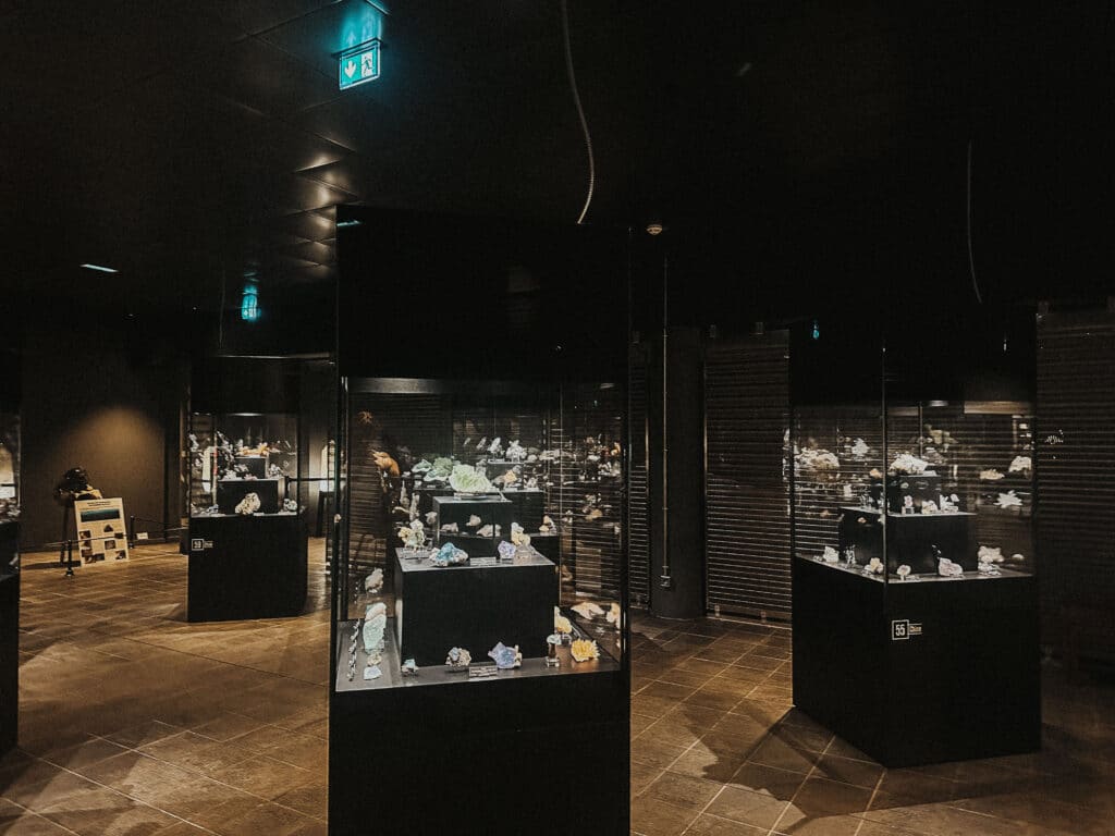 Wide view of the main exhibit room at the Chamonix Crystal Museum, showing multiple illuminated mineral display cases.