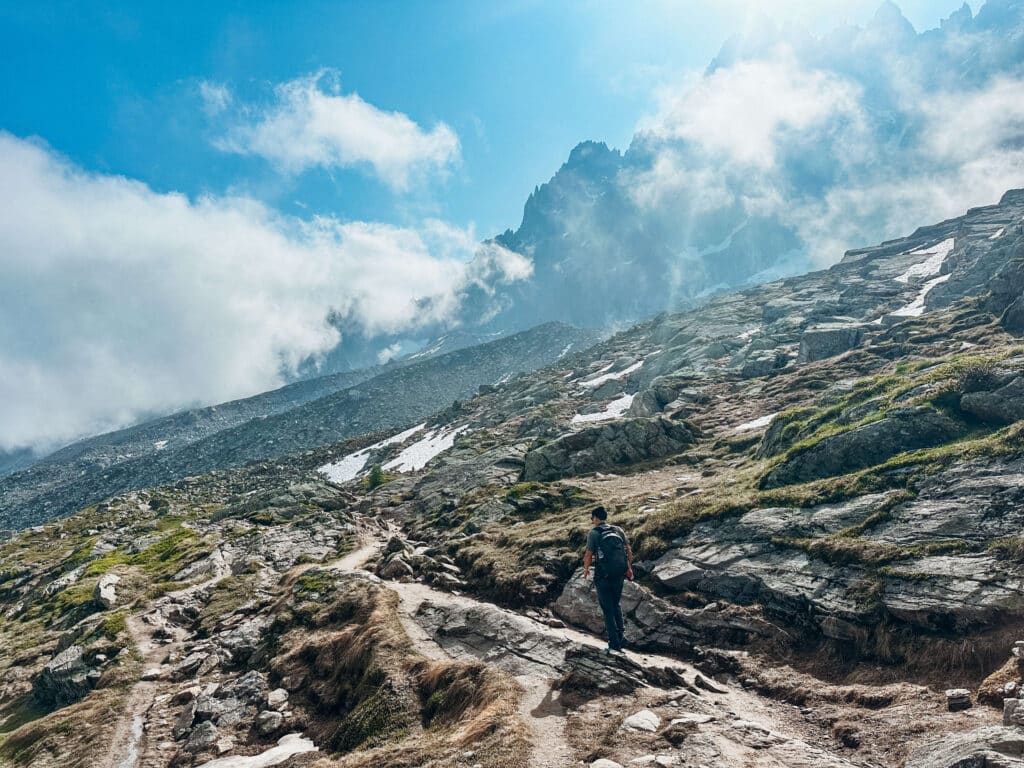 Dramatic ridgeline view of the Grand Balcon Nord trail cutting across alpine terrain with shifting clouds overhead.