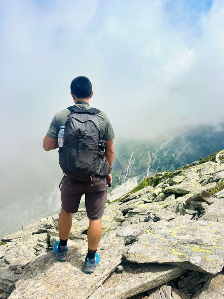 Hiker standing on a rocky outcrop, looking into the mist above Chamonix’s Grand Balcon Nord trail approaching Signal Forbes