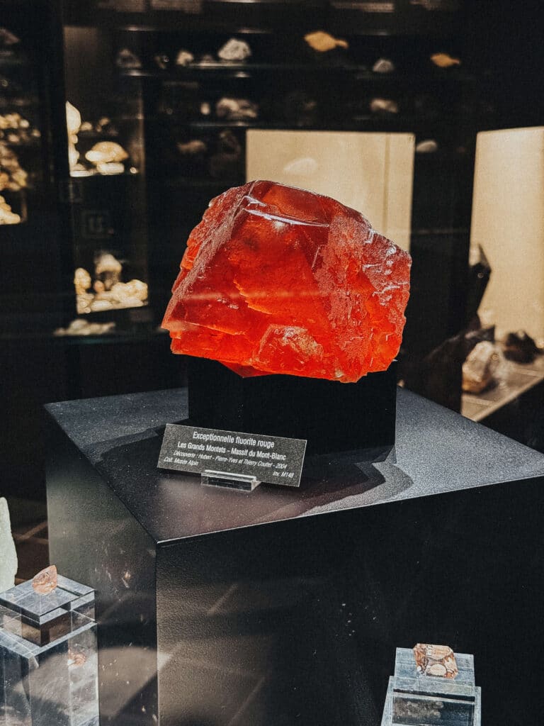 Deep red fluorite crystal displayed prominently in a black glass case at the Chamonix Crystal Museum.