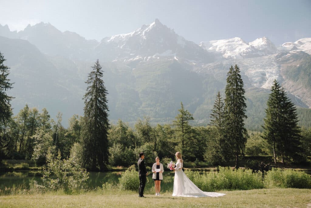 Bride and groom walking away down the aisle at Les Gaillands with mountain peaks in the distance. Photo credit: Mathilde Rietsch