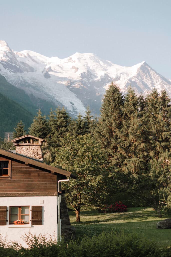 View of a wooden chalet and garden with Mont Blanc towering in the background on a clear summer morning in Chamonix. Photo credit: Mathilde Rietsch