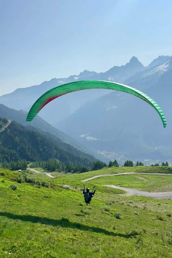 Tandem paraglider in full flight above green alpine meadows in Chamonix, France