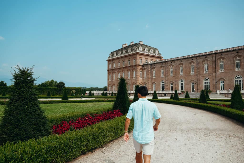 Traveler walking through the formal garden, approaching the rear entrance of the palace