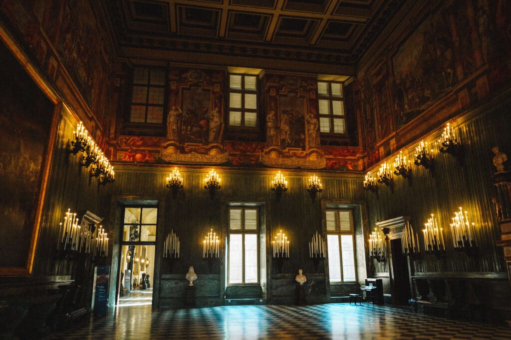 Dimly lit hall of the swiss guards room with reflective floors and illuminated doorways in the Royal Palace of Turin.