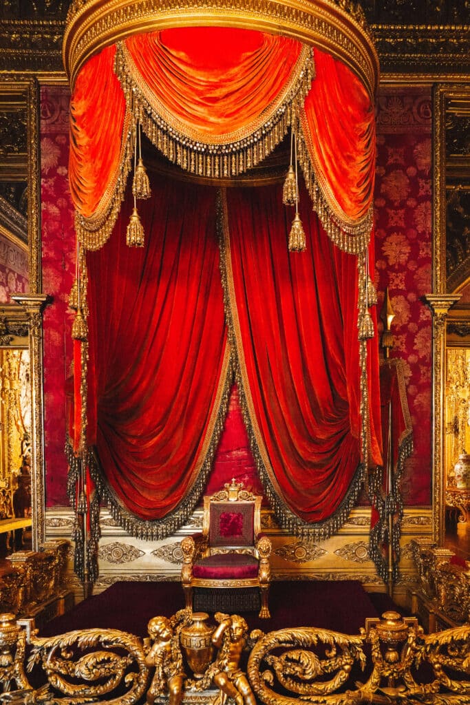 Throne room featuring a red velvet canopy and ornate gold detailing inside the Royal Palace of Turin.