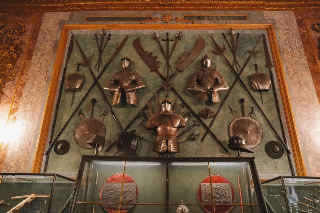 Display of historical armor and weapons in a symmetrical arrangement inside the Royal Armory of Turin.