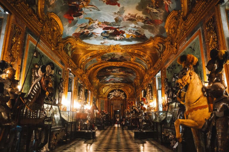 Lavishly decorated hallway lined with suits of armor and frescoed ceilings in the Royal Armory of Turin.