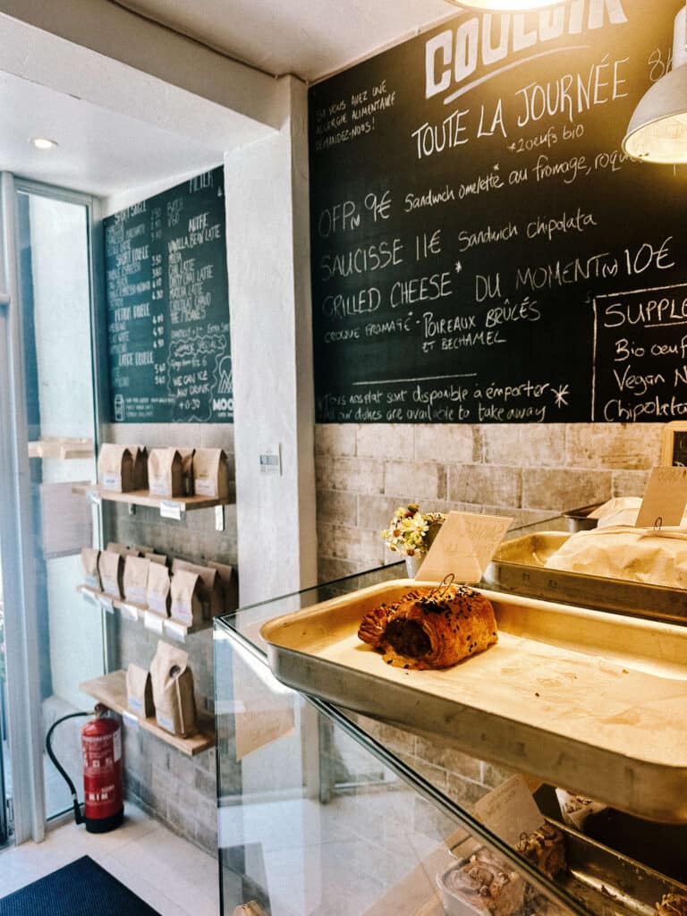Interior shot of Couloir Chamonix with a chalkboard menu and a tray of pastries inside a modern café.