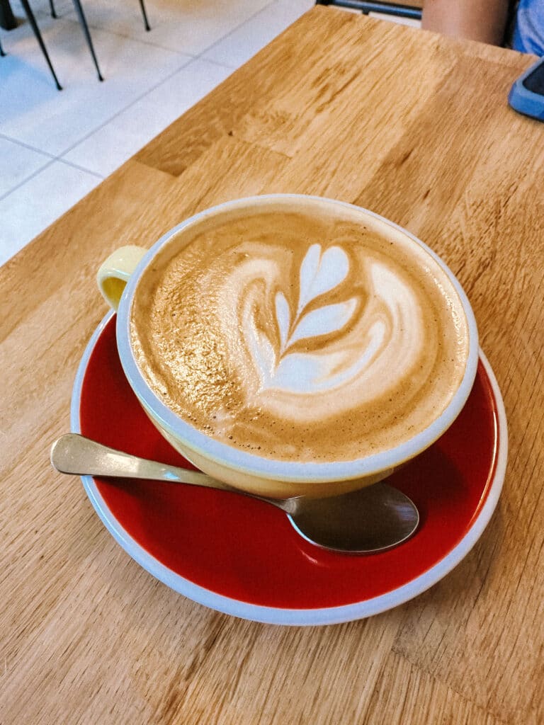 Cappuccino in a yellow cup with latte art, served on a bright red saucer at Couloir Chamonix.