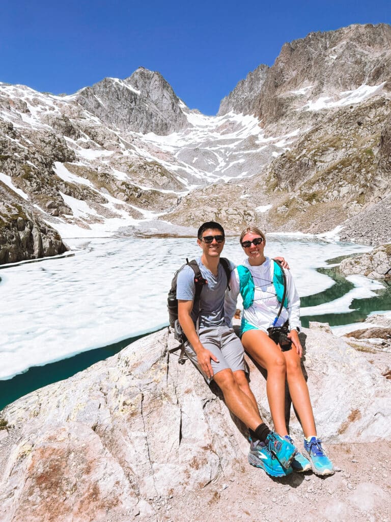 Two happy hikers posing in front of Lac Blanc, the most beautiful lake in the French Alps