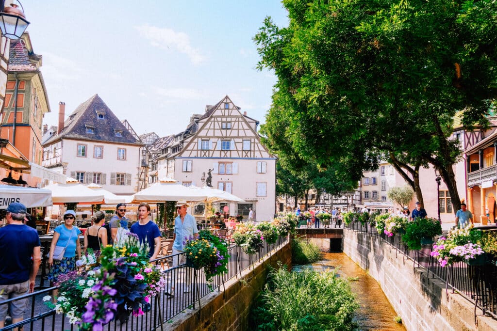 Wooden bridge and flower boxes overlooking canal-side restaurants in Colmar’s Petite Venise