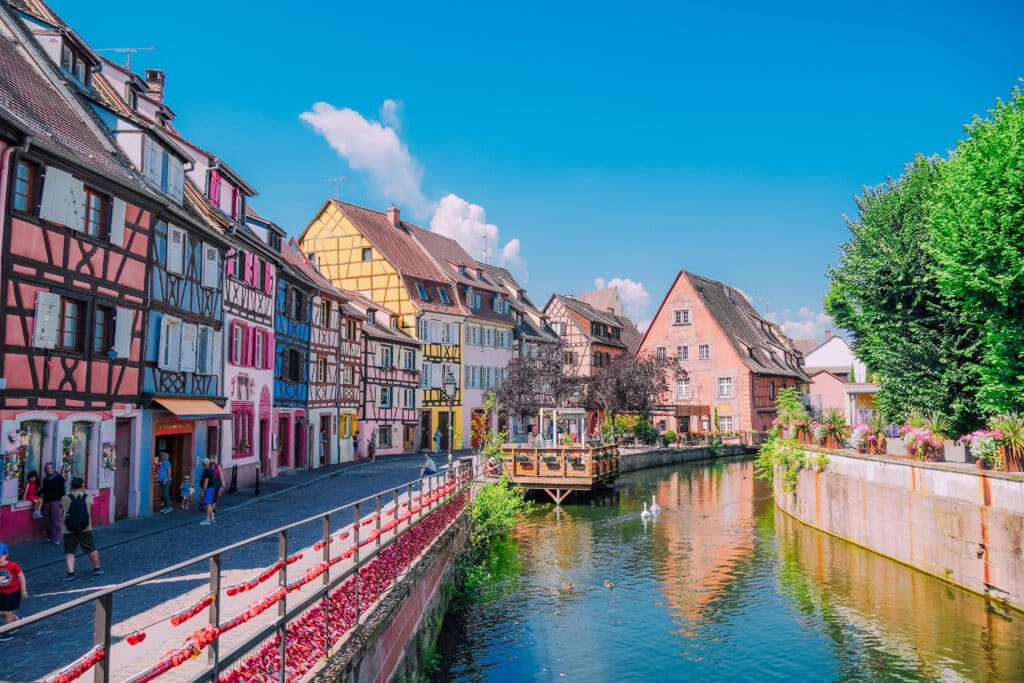 Centered view down a canal with symmetrical reflections of timbered houses in Colmar