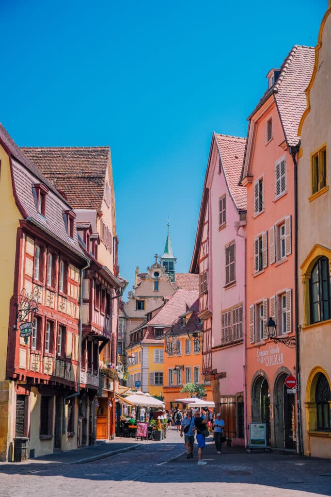 Narrow pedestrian street with peach and ochre buildings in central Colmar