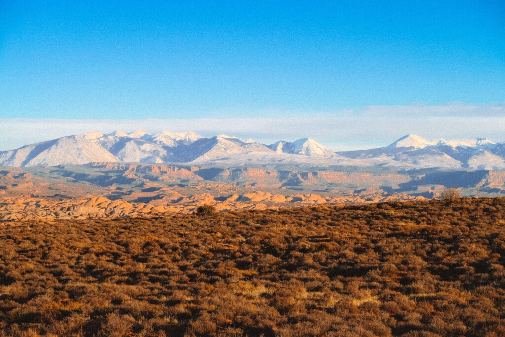 Wide desert vista with distant snowy La Sal mountains under crisp winter light