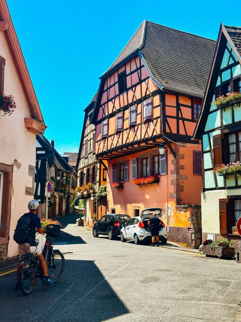 Cyclist in front of half-timbered buildings along a charming alleyway in Riquewihr