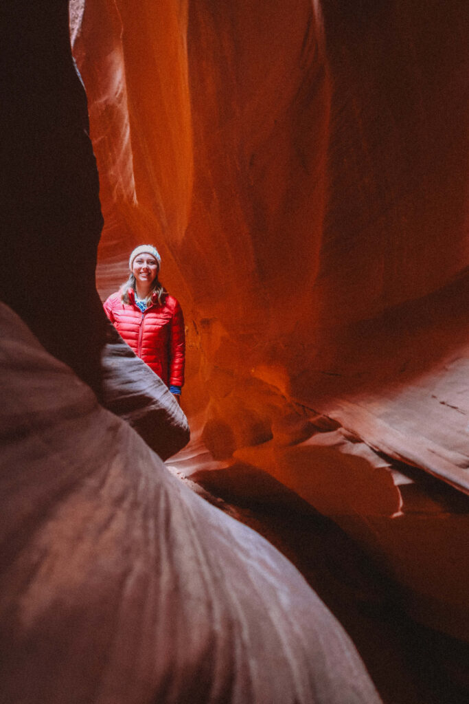 Solo hiker standing quietly inside a narrow passage of Wind Pebble Canyon during a private Navajo tour near Page, AZ