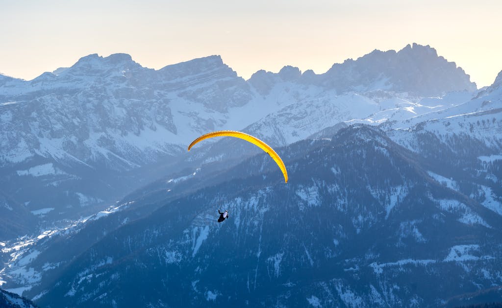 A paraglider soars above the snowy Dolomites in Trentino-South Tyrol, Italy during winter.