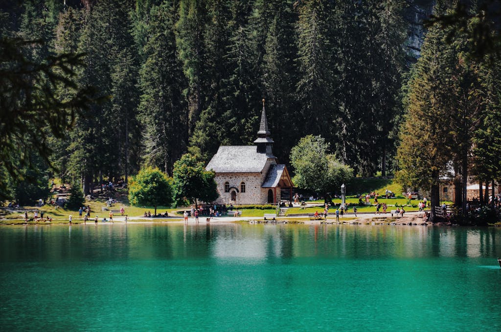 A picturesque church by a serene lake surrounded by lush forest, offering a peaceful countryside view.