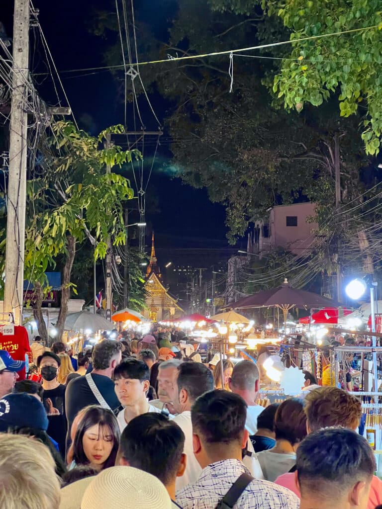 Crowds walking through Chiang Mai’s lively Sunday Night Market under string lights.