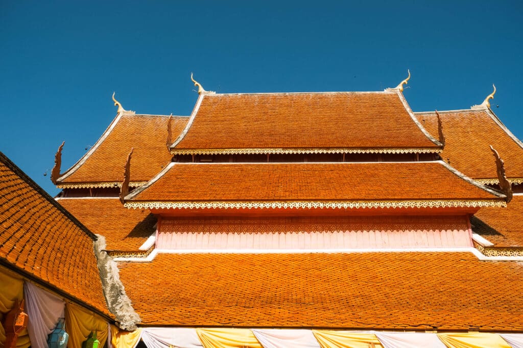 Tiered orange temple roof with intricate golden trim at Doi Suthep