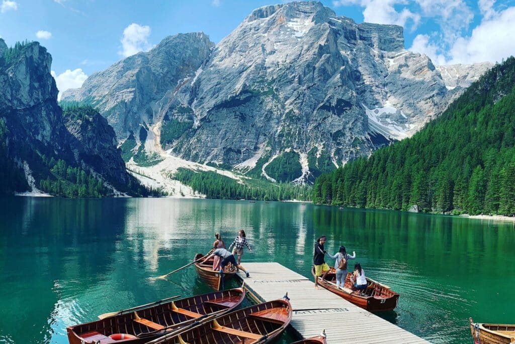 Exploring the serene Lake Braies with wooden boats against the backdrop of towering mountains in Italy.