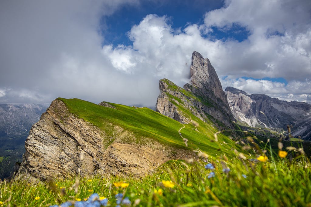 Majestic Seceda mountain peaks with vibrant green slopes under cloudy sky.
