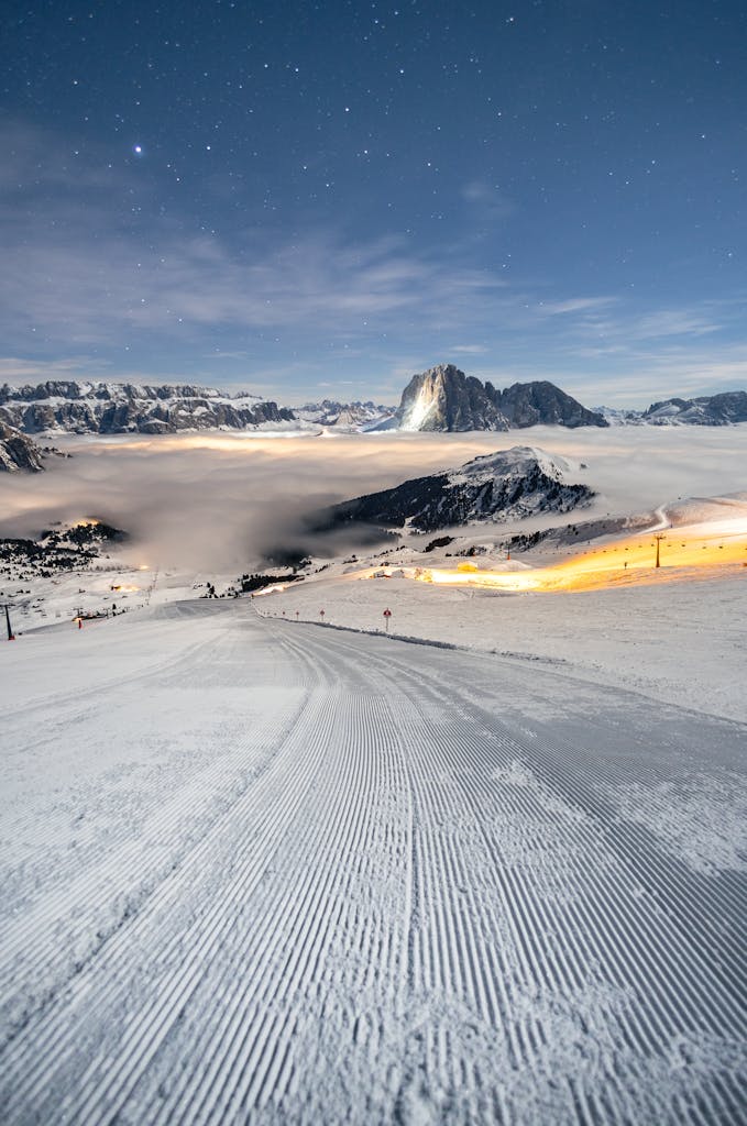 Night view of a snow-covered ski slope under a starry sky in the Dolomites, Italy.