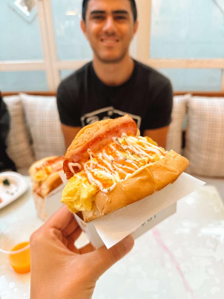 Guest holding the daily egg sandwich breakfast at Pastell Oldtown Chiang Mai.