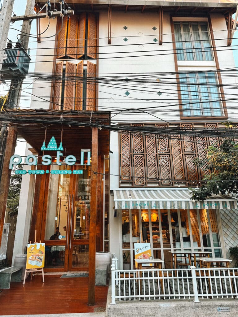 Exterior view of Pastell Oldtown Chiang Mai with hotel signage and seating area.